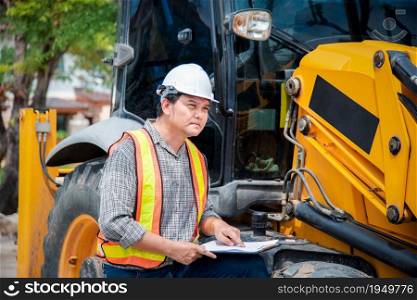 Asian man civil construction engineer worker or architect with helmet and safety vest working and holding a paper board note for see blueprints or plan at a building or construction site. Man construction engineer at construction site