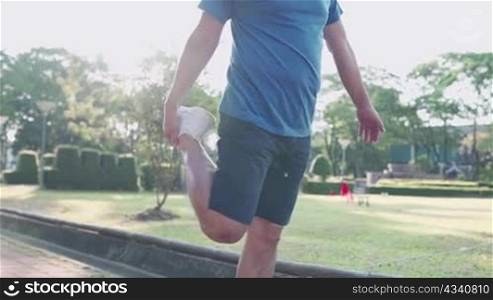 asian man doing standing leg stretching at public park before exercise, joint ligament bone problem, holding up leg, injury prevention, active lifestyle, warm up before running, burning calories