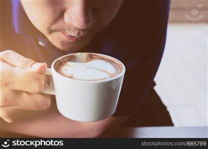 Asian man drink coffee in a modern style coffee shop - people with coffee cup easy lifestyle concept
