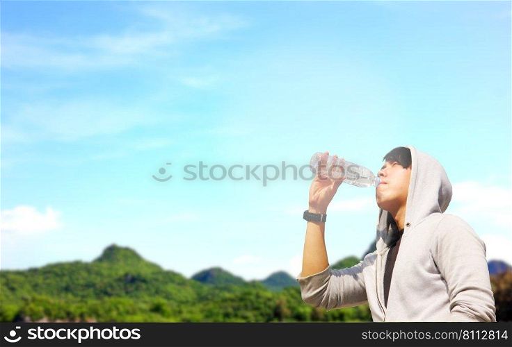Asian man drinking water from plastic bottle with blue sky  nature background