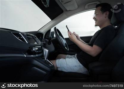 Asian man driver using smart phone in car .