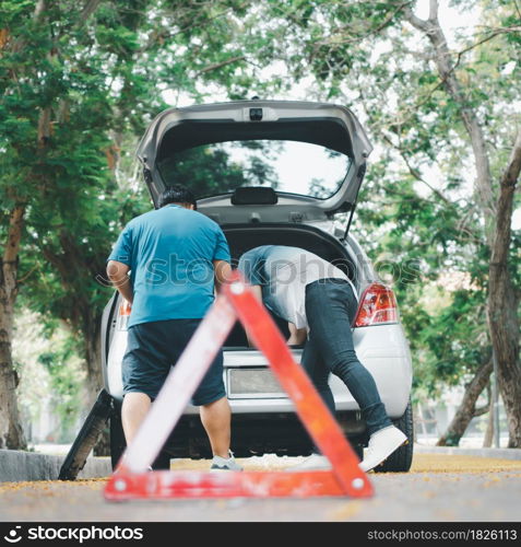 Asian man find tools in the car for car repair after a car breakdown on street. Concept of vehicle engine problem or accident and emergency help from Professional mechanic