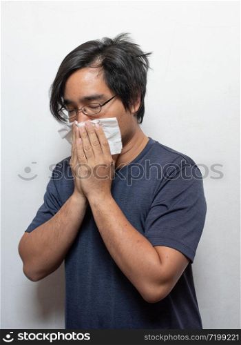 Asian man getting cold or flu,he is coughing to clear throat with hand holding tissue paper closing his mouth isolated on white background Illness and sickness concept.