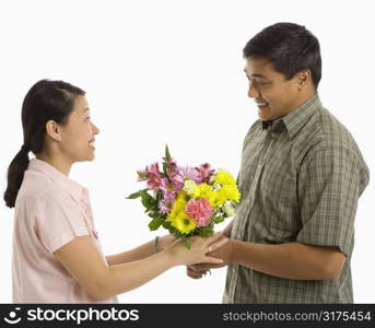 Asian man giving Asian woman a bouquet of flowers.