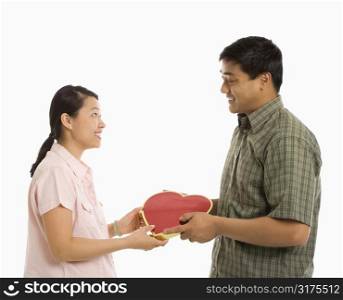 Asian man giving Asian woman a heart shaped box.