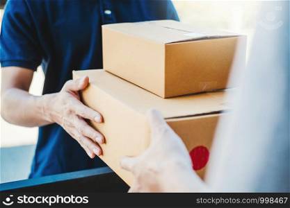 Asian Man hand accepting a delivery boxes from professional deliveryman at home