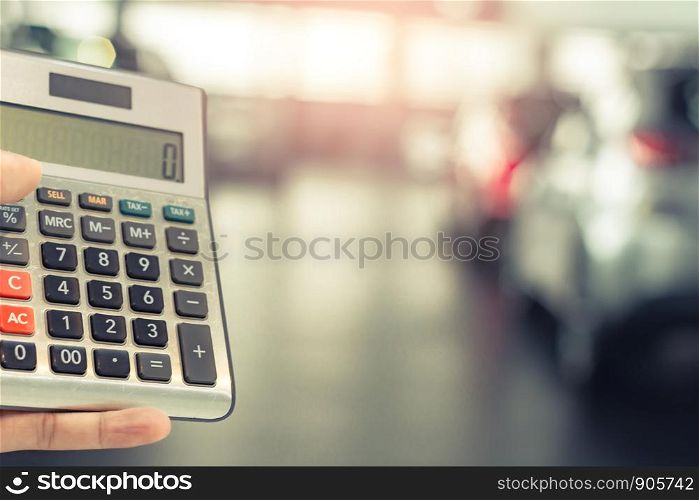 Asian man holding calculator for business finance on car showroom blurred bokeh background.for automotive automobile or transportation transport