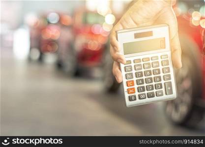 Asian man holding calculator for business finance on car showroom blurred bokeh background.for automotive automobile or transportation transport