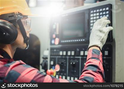 Asian man inspector engineer industry control monitor computer Press button machines factory inspection in industry wears helmet working metalwork control in industrial In a plastic factory for car