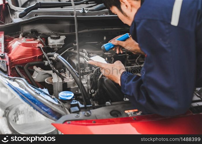 Asian Man mechanic inspection Shine a torch car engine checking bug in engine from application smartphone.Red car for service maintenance insurance with car engine.for transport automobile automotive auto repair car