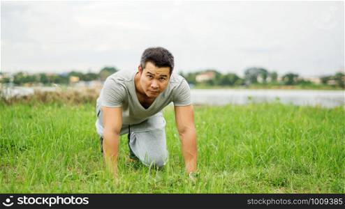 Asian man prepares for a workout at the public park, soft focus.