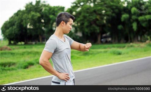Asian man prepares for a workout at the public park, soft focus.