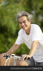 asian man tooth smiling face riding on bicycle in green public park