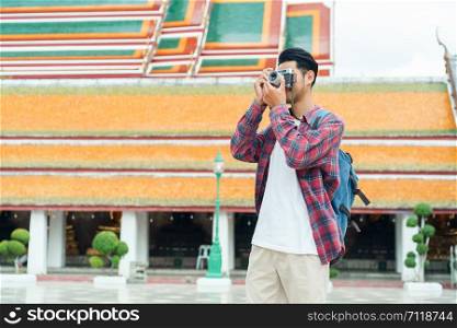 Asian man tourist walk taking photo with film camera at Wat Suthat Thepwararam Ratchaworawihan Bangkok, Thailand, Solo travel and backpacker concept