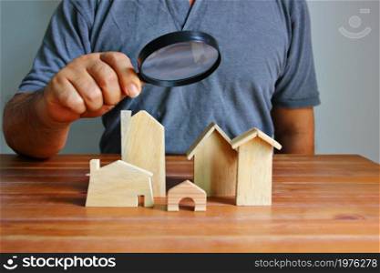 Asian man using magnifying looking to wood model home