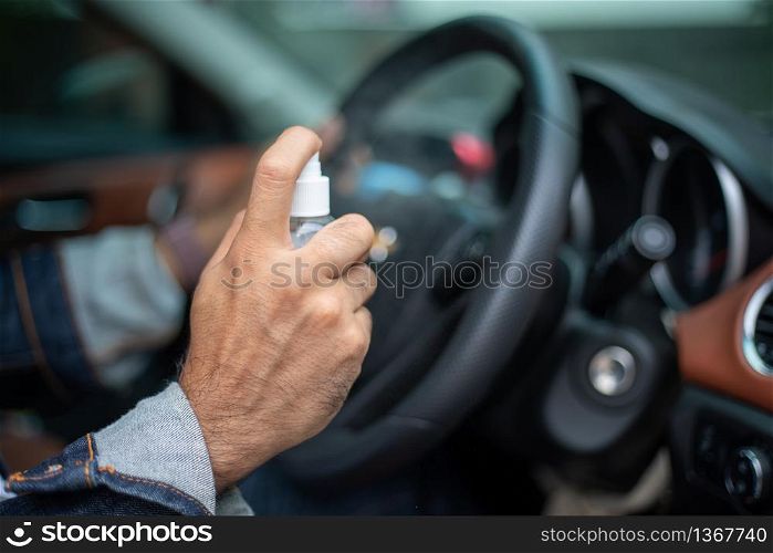 Asian man using spray alcohol to clean the car for coronavirus protection
