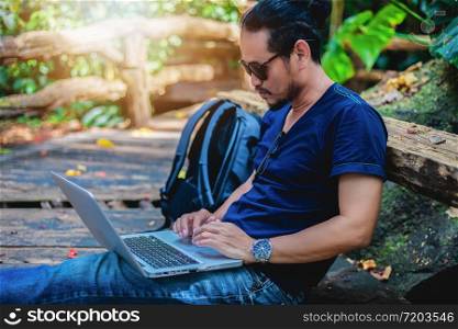 Asian man working and checking photo on laptop at outdoor nature and He is relaxing, enjoying on travel