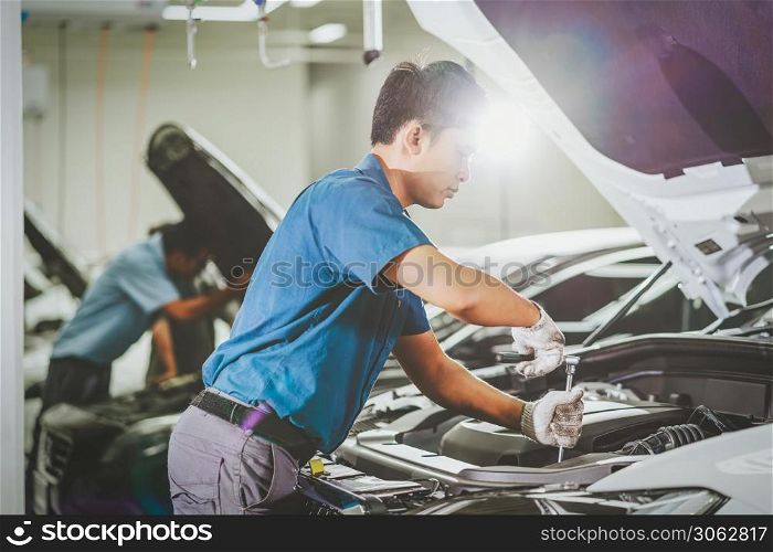Asian mechanic Checking and repairing the car in maintenance service center which is a part of showroom, technician or engineer professional work for customer, car repair concept
