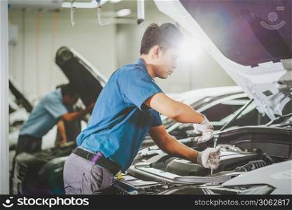 Asian mechanic Checking and repairing the car in maintenance service center which is a part of showroom, technician or engineer professional work for customer, car repair concept