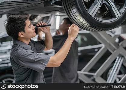 Asian mechanic Checking and torch tire in maintainance service center which is a part of showroom, technician or professional work for customer concept