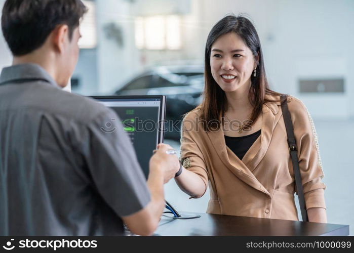 Asian mechanic recieving the automatic car key for checking at maintainance service center for in showroom