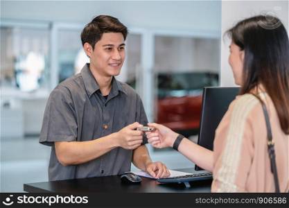 Asian mechanic recieving the automatic car key for checking at maintainance service center for in showroom