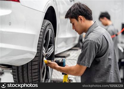 Asian mechanics checking the car wheels at maintainance service center for in showroom which is a part of showroom, technician or engineer professional work for customer, car repair concept