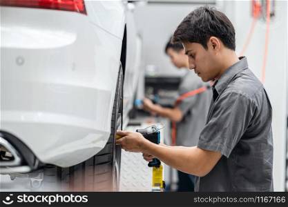 Asian mechanics checking the car wheels at maintainance service center for in showroom