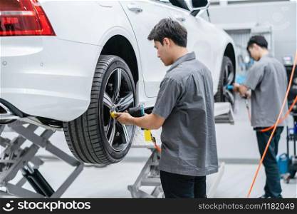 Asian mechanics checking the car wheels at maintainance service center for in showroom