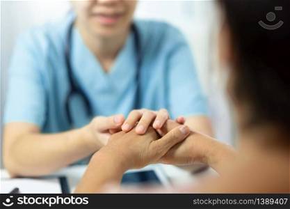 Asian medical nurse talking giving advice and comforting senior woman patient in office room. Female elderly being reassured by Physician with holding hands together in hospital.