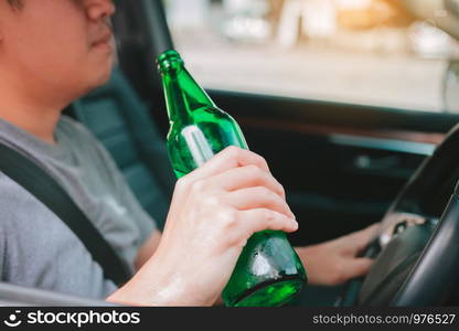 Asian men are breaking the traffic rules by holding a bottle of beer and drinking while driving.