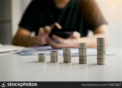 Asian men are calculating about finances about the cost or future investment at home while the coins are arranged with the idea of saving.