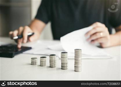 Asian men are calculating about finances about the cost or future investment at home while the coins are arranged with the idea of saving.