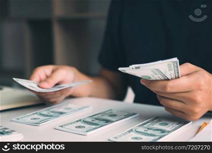 Asian men are holding banknotes in cash and placed on the table with the idea of saving money.