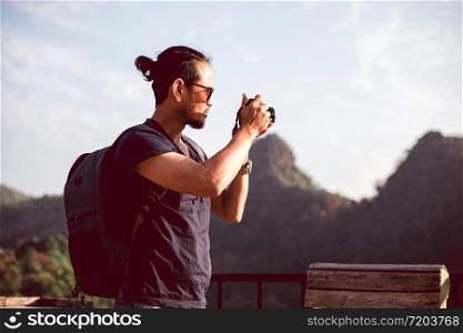 Asian men backpacks and traveler walking together and happy are taking photo on mountain ,Relax time on holiday concept travel