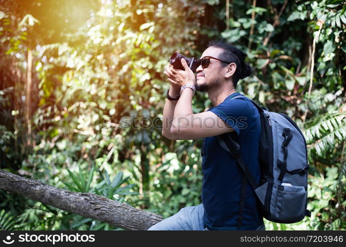Asian men backpacks and traveler walking together and happy are taking photo on forest ,Relax time on holiday concept travel