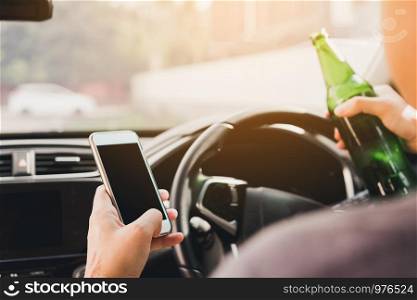 Asian men drink alcohol in the car and using mobile phones while driving.