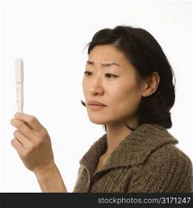 Asian mid adult woman holding up pregnancy test.