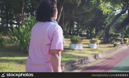 Asian middle age female walking at recreational park in morning at public park, elderly sport wears, relaxing exercise, happy retirement healthy lifestyle, fat burning, weight controlling, cardiology