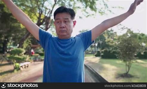Asian middle age man doing warm up exercise at the park, swing and rotating arms shoulder, retirement lifestyle fitness healthcare, workout on sunny day, vitality wellness, senior illness prevention