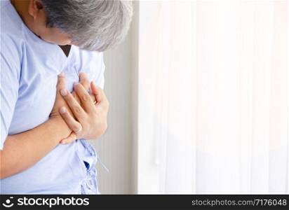 Asian middle age man with chest pain suffering from heart attack in white hospital patient room. Healthcare of Myocardial infarction concept