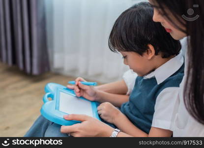 Asian mom teaching cute boy to drawing in chalkboard together. Back to school and Education concept. Family and Home sweet home theme. Preschool kids theme.