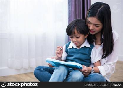 Asian mom teaching cute boy to drawing in chalkboard together. Back to school and Education concept. Family and Home sweet home theme. Preschool kids theme.