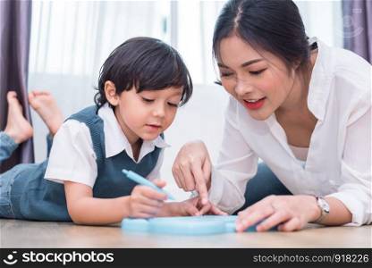Asian mom teaching cute boy to drawing red heart in board with color pen. Back to school and Education concept. Family and Home sweet home theme. Preschool kids theme. Front view angle
