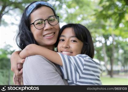 Asian mother and daughter hug each and smiling other at the park, Happy family concept.