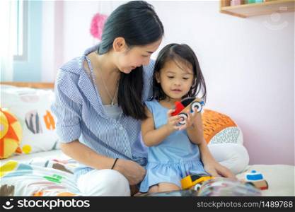 Asian mother and daughter playing toy in house
