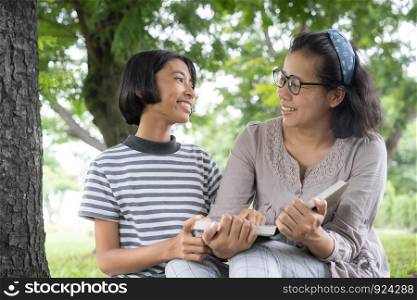 Asian mother and daughter reading book in the garden
