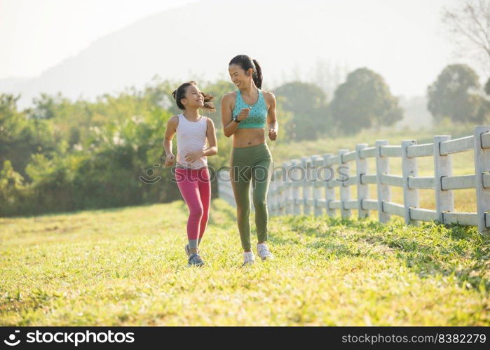 Asian mother and daughter run in forest park. runner trying running shoes getting ready for run. Jogging girl exercise motivation health and fitness. warm sunlight flare.