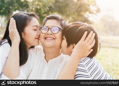Asian mother and son show love for grandmother by kiss cheeks at the park in the morning. The concept of family lifestyle on the holiday