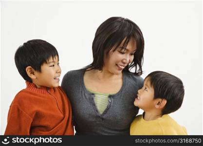 Asian mother and two sons smiling at eachother.